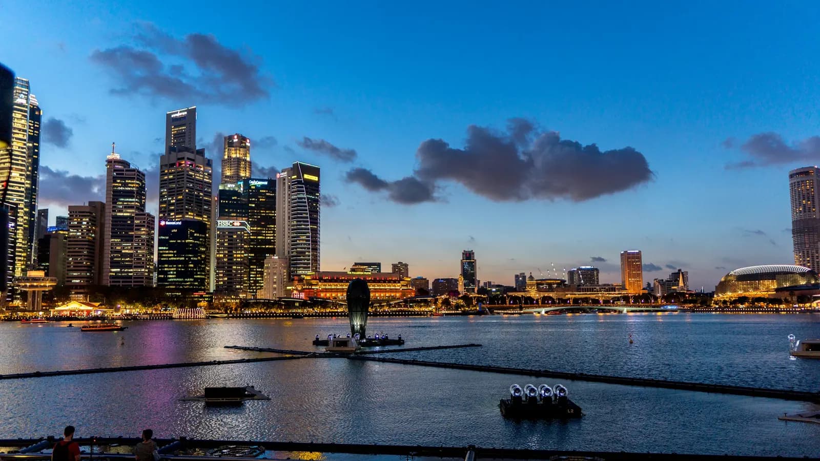 The skyline of Singapore's Central Business District across Marina Bay at dusk.