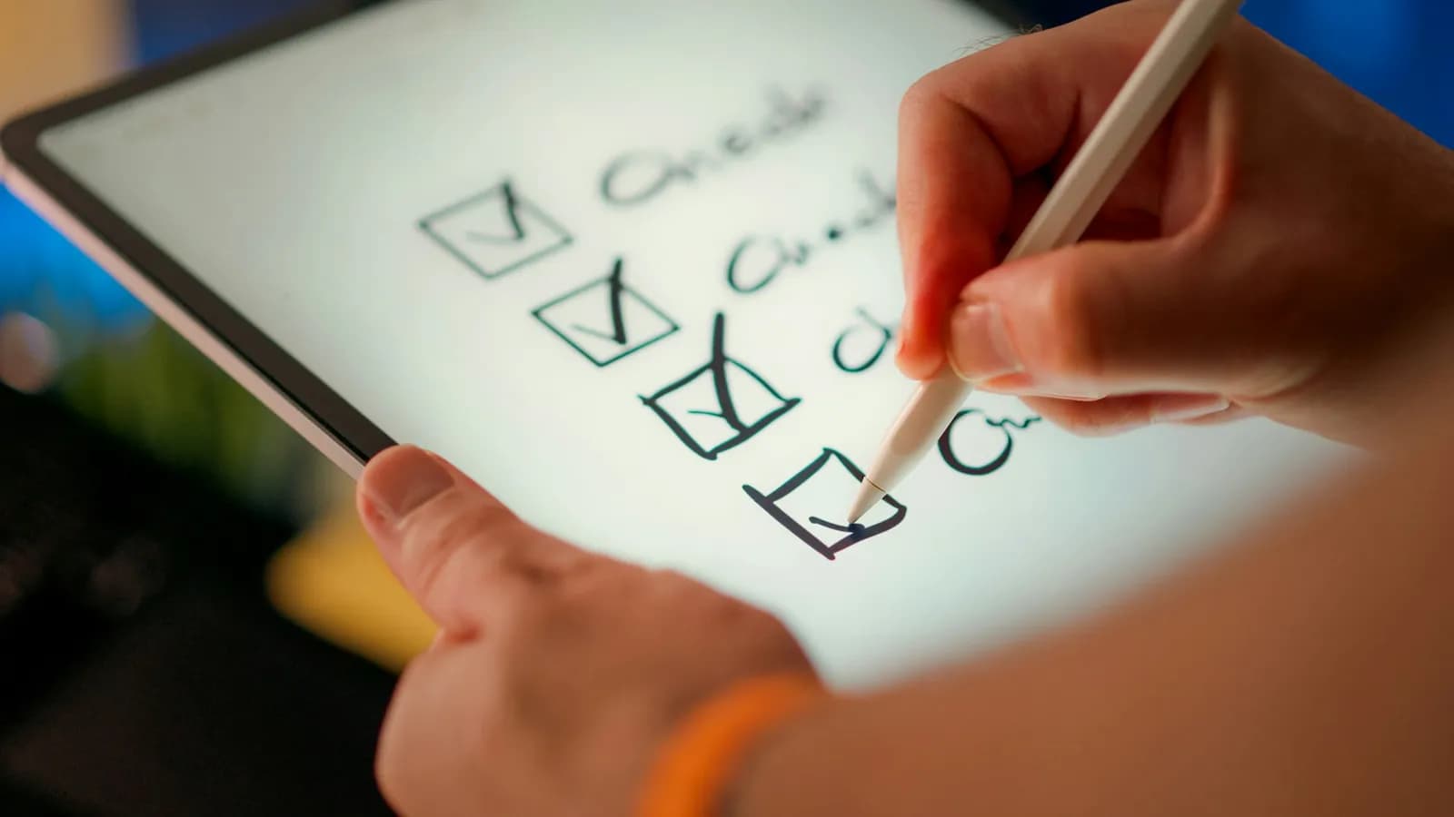 A hand holding a white stylus ticks the fourth of four handwritten checkboxes on a tablet screen.